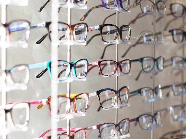 Rows of eyeglasses on a wall rack in an optical store