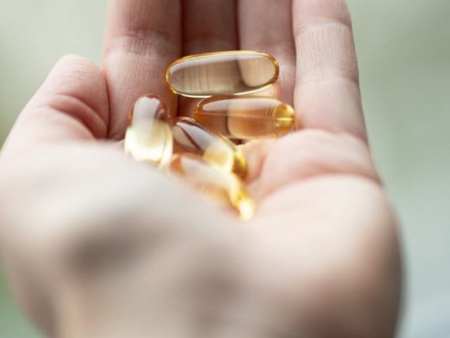 Golden supplement capsules held in an open palm